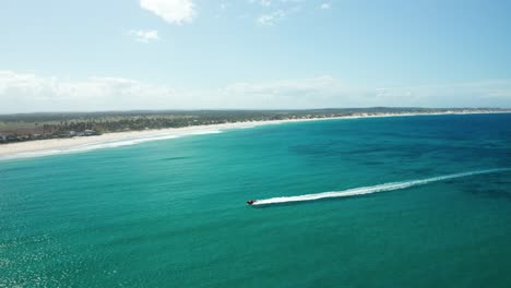 Long-shot-from-a-drone-tracking-a-speedboat-heading-toward-the-beach-in-Tofo,-Mozambique