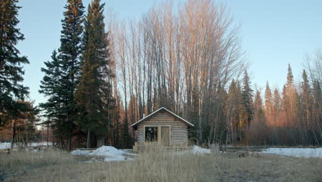 Wide-shot-of-perfect-log-cabin-surrounded-by-trees-at-sunrise