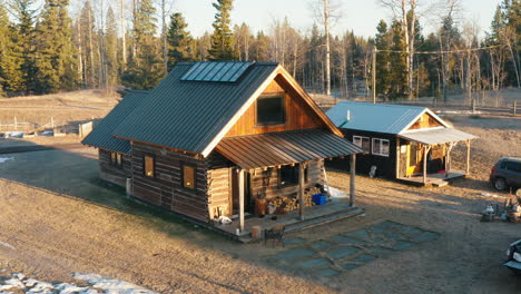 Aerial-orbit-around-log-cabin-house-in-a-snowy-forest-field