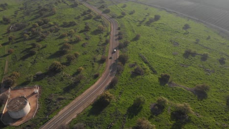 Aerial-tilt-up-following-Car-on-Countryside-Road-surrounded-grass,-Foggy---Golan-Heights
