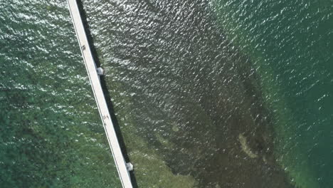 AERIAL---Reflection-on-water-around-bridge-of-Samana,-Dominican-Republic,-top-down