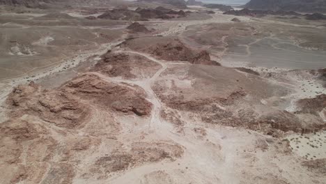 Aerial-view-over-cliffs-and-a-desert-road-in-the-Timna-Valley,-Israel---reverse,-tilt,-drone-shot