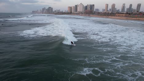 Aerial-view-of-surfers-on-the-coast-of-Tel-Aviv,-Israel---pull-back,-drone-shot