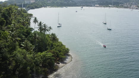 AERIAL---Sailboats-around-port-of-Samana,-Dominican-Republic,-wide-reverse-shot