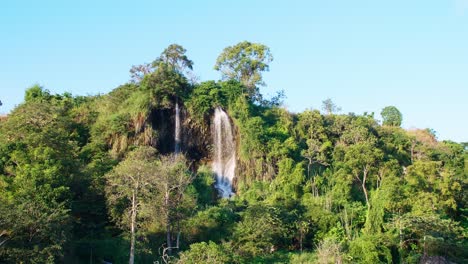 Ein-Weiter-Blick-Auf-Den-Natürlichen-Wasserfall,-Der-Den-Berg-Hinunterfließt,-Wird-Von-Der-Abendsonne-In-Thailand-Beleuchtet