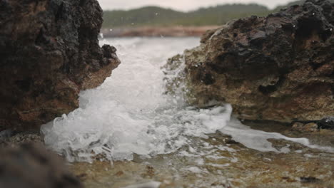 Waves-crashing-between-rocks-on-the-beach,-slow-motion-medium-shot