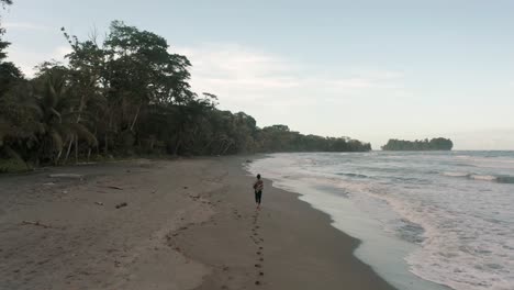 Tourist-Walking-On-The-Sand-And-Leaving-Footprints-At-The-Beach-In-Punta-Mona,-Costa-Rica---Drone-Shot