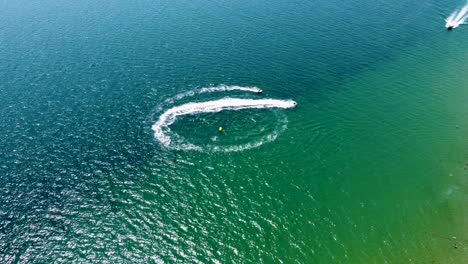 4K-drone-clip-of-boats-and-jet-skis-performing-water-sports-next-to-an-exotic-beach-in-Sveti-Vlas,-Bulgaria