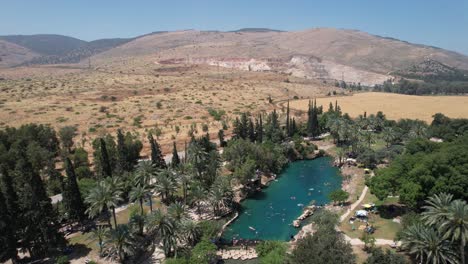 Aerial-view-around-a-green-lagoon,-in-Gan-HaShlosha-National-Park,-in-Israel---orbit,-drone-shot