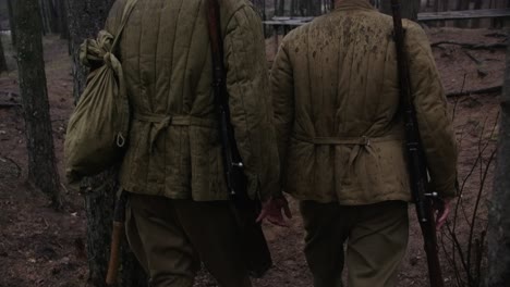 Dos-Soldados-De-La-Segunda-Guerra-Mundial-Caminando-En-Un-Bosque-Con-Rifles,-Cascos-Y-Botas