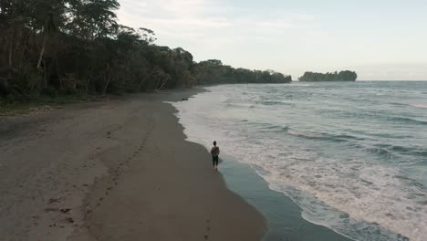 Back-View-Of-Person-Walks-Through-Sea-Waves-At-Punta-Mona-Shoreline-In-Costa-Rica