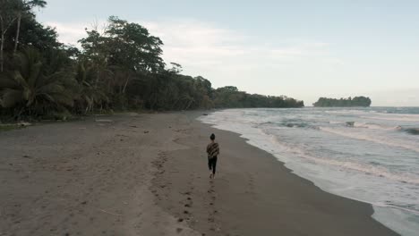 Weibliche-Touristin,-Die-Am-Tropischen-Strand-Von-Punta-Mona-In-Costa-Rica-Spaziert---Luftdrohnenaufnahme