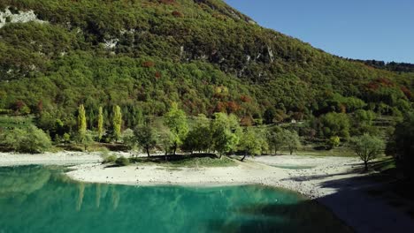 Lago-De-Agua-Azul-De-Montaña-En-Los-Dolomitas-De-Los-Alpes-Italianos-Con-árboles-Y-Picos-Con-Una-Pequeña-Isla-Aérea-De-Drones