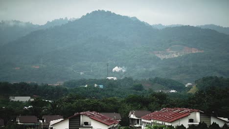 A-factory-near-a-mountain-range_produce-a-white-smoke_view-from-residential-area_wide-shot_long-shot_50fps