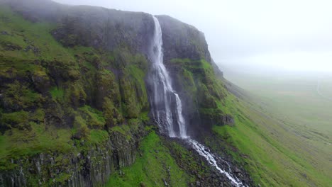 Malerischer-Wasserfall,-Der-An-Einem-Nebligen-Tag-In-Moosige-Und-Felsige-Bergklippen-Fließt