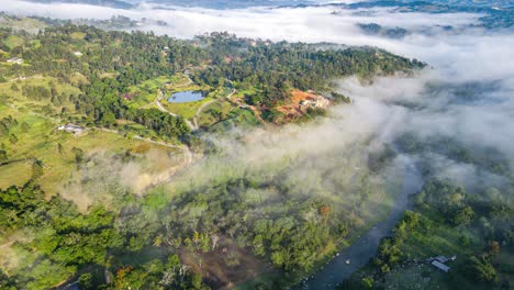Amanecer-En-Jarabacoa-Sobre-El-Río-Yaque-Del-Norte-Con-Nubes-Bajas,-Impresionante-Clima-Caribeño-En-La-República-Dominicana,-Con-árboles,-Vegetación-Y-Un-Pequeño-Lago-Rodeado-De-Naturaleza