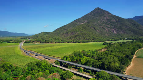 Scenic-Road-Among-Green-Fields-And-Mountains-In-Cairns,-Queensland,-Australia---aerial-drone-shot