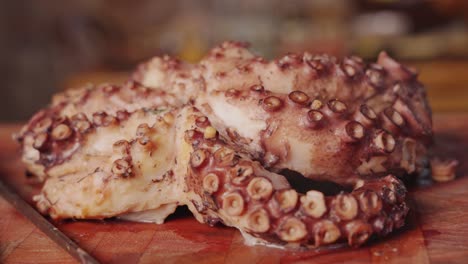 Extreme-close-up-dolly-in-and-out-of-half-cooked-steaming-hot-octopus-on-a-wooden-chopping-board,-seafood-dish-preparation,-cooking-concept-shot