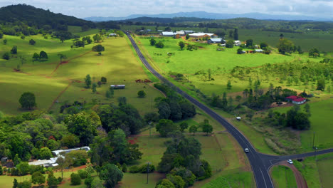 Aerial-View-Of-Countryside-Road-Among-Green-Fields-In-Atherton-Tablelands,-Queensland,-Australia---drone-shot