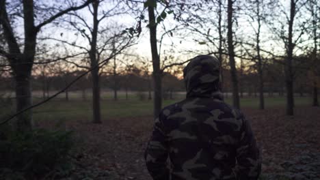 A-man-wearing-a-camouflage-jacket-in-a-slightly-dark-moody-forest
