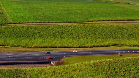 Aerial-View-Of-Cars-Driving-Through-Sugar-Cane-Fields-In-Cairns,-QLD,-Australia