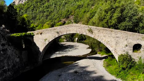 Aerial:-man-walking-on-a-stone-ancient-river-bridge