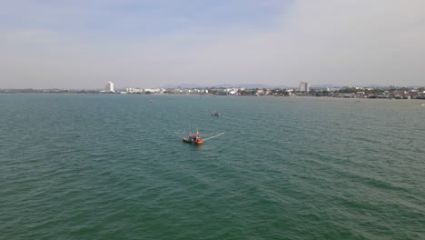Aerial-footage-towards-a-fishing-boat-revealing-two-more-and-the-city-of-Pattaya-in-Chonburi,-Thailand