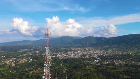 Torre-De-Comunicación-En-La-Vista-Aérea-De-Las-Montañas-Con-La-Naturaleza-Y-La-Ciudad-En-La-Parte-Trasera