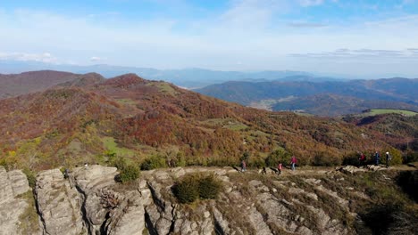 Aerial:-several-hikers-walking-along-a-very-narrow-mountain-crest-in-autumn-season