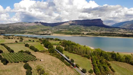 Aerial:-old-diesel-train-traveling-by-a-lake