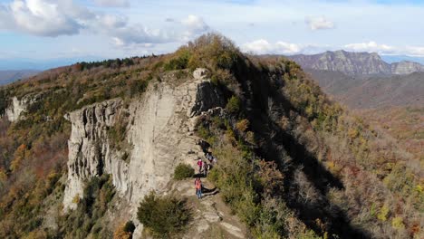 Aerial:-several-hikers-walking-along-a-very-narrow-mountain-crest-in-autumn-season