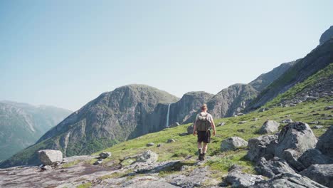 Rocky-Mountains-In-Der-Nähe-Von-Mardalsfossen-Mit-Rucksacktouristen,-Die-An-Einem-Sonnigen-Tag-In-Norwegen-Hinüber-Gehen