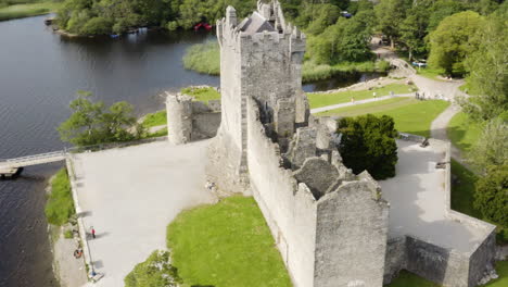 AERIAL---Ross-Castle-in-Killarney-National-Park,-Ireland,-rising-tilt-down-circling