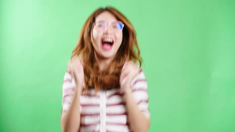 Cheerful-young-Asian-woman-with-eyeglasses-raising-hands-up,-shaking-and-having-fist-pump-from-happiness,-smiling-woman-face,-green-screen-background