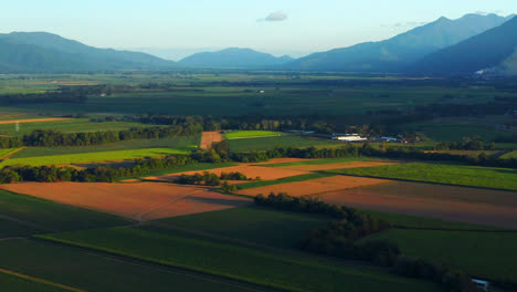 Lush-Farm-Fields-And-Mountains-In-Cairns,-Queensland,-Australia-At-Sunrise---aerial-shot