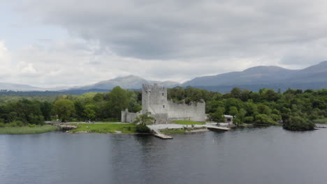 AERIAL---Ross-Castle-in-Killarney-National-Park,-Ireland,-forward-wide-rising-shot
