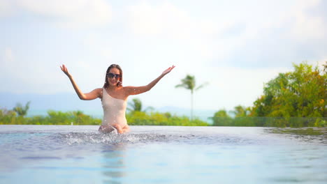 An-attractive-woman-sitting-on-the-edge-of-a-swimming-pool-playfully-splashes-water-into-the-air