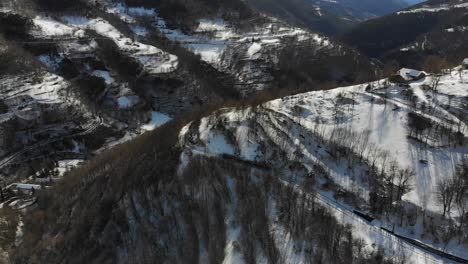 Aerial:-mountain-short-train-descending-among-snowy-mountains