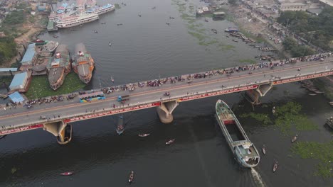 A-cargo-ship-passing-under-buriganga-river-bridge---aerial-top-down-drone-flight-shot