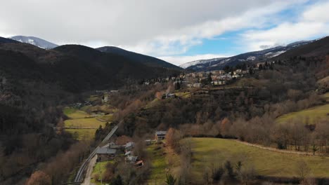 Luftaufnahme:-Annäherung-An-Eine-Kleine-Bergstadt-In-Einer-Bergigen-Landschaft-Mit-Schneebedeckten-Bergen-Im-Hintergrund