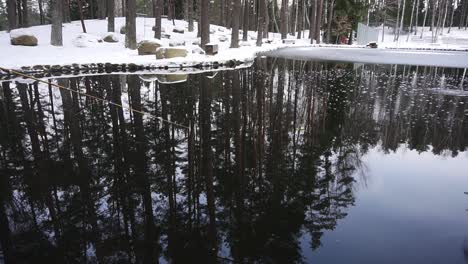 person-is-fishing-in-the-pond-in-the-snowy-winter,-there-is-fishing-rod-in-the-shot