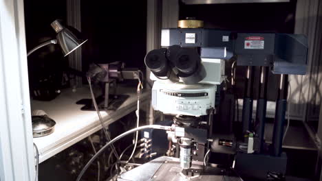 Closeup-of-a-high-tech-laboratory-microscope-in-a-semidark-office