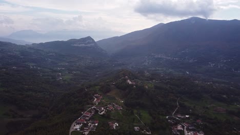 Aerial-forward-view-of-Pietraroja-valley-in-mountain-landscape-and-clouds-on-the-horizon