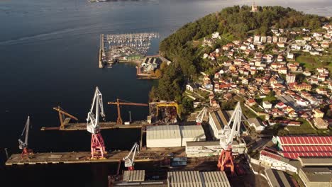 aerial-view-of-Vigo-city-in-Spain,-crane-working-in-shipping-port-harbour-for-import-export-goods-in-big-container-coming-oversea