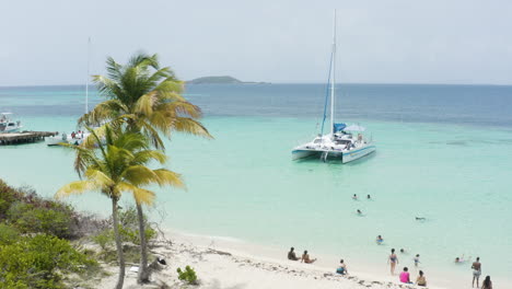 AERIAL---People,-catamaran-boat,-turquoise-waters,-Cayo-Icacos,-Puerto-Rico,-reverse