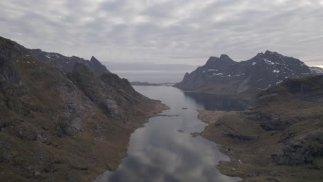 Aerial-drone-view-overlooking-a-narrow,-reflecting-area-of-the-Reinefjord,-in-Lofoten,-Norway