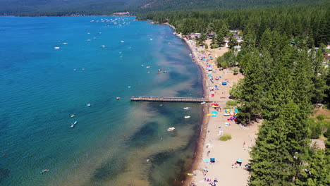Aerial-view-of-people-relaxing-on-a-sandy-beach-surrounded-by-a-pine-forest-in-Lake-Tahoe