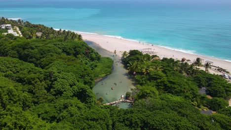 River-flowing-into-a-beach,-the-shortest-in-the-Caribbean,-Los-Patos,-Barahona,-Dominican-Republic-stunning-river-next-to-the-beach-aerial-view
