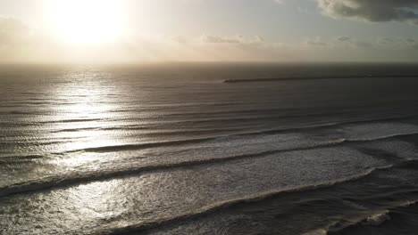 Ocean-waves-at-sunset,-view-from-drone
