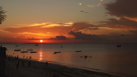 TIME-LAPSE---Sunset-on-the-beach-with-boats,-Nungwi,-Zanzibar,-Tanzania,-wide-shot